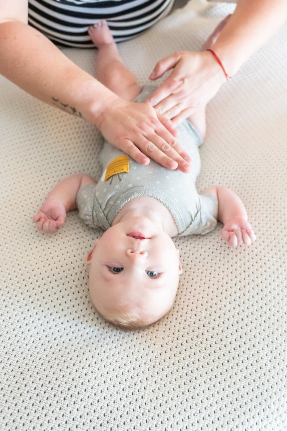 Photo of baby lying upside down on a massage table.